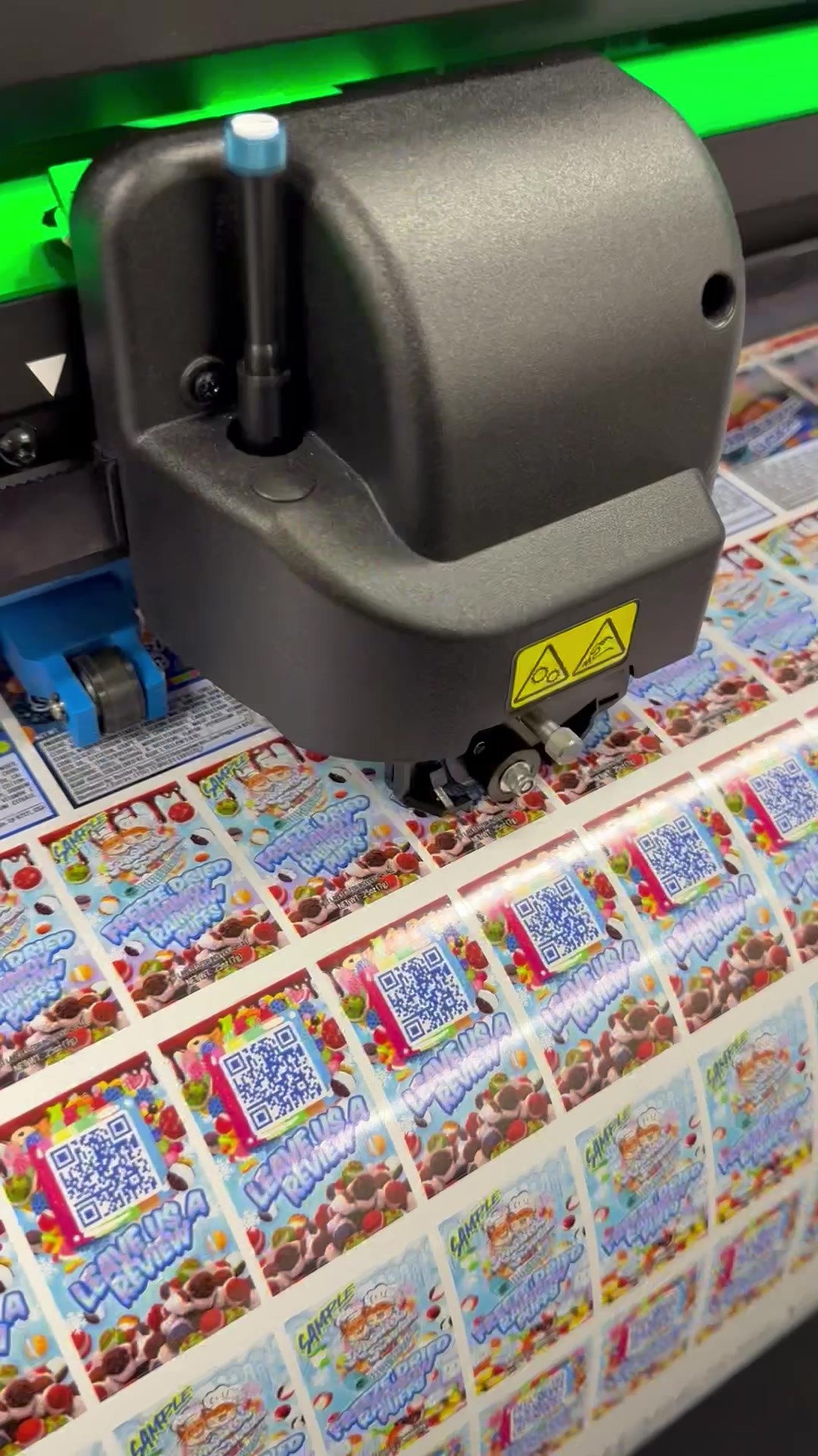 A cutter working on a sheet of colorful custom labels
